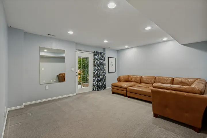 Recessed lighting, light gray wall finish, gray carpeting, white trim, and a glass-paneled door