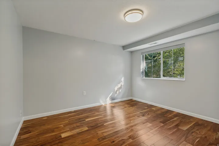 Wood-finish flooring, white trim, recessed window, and flush-mount ceiling light fixture