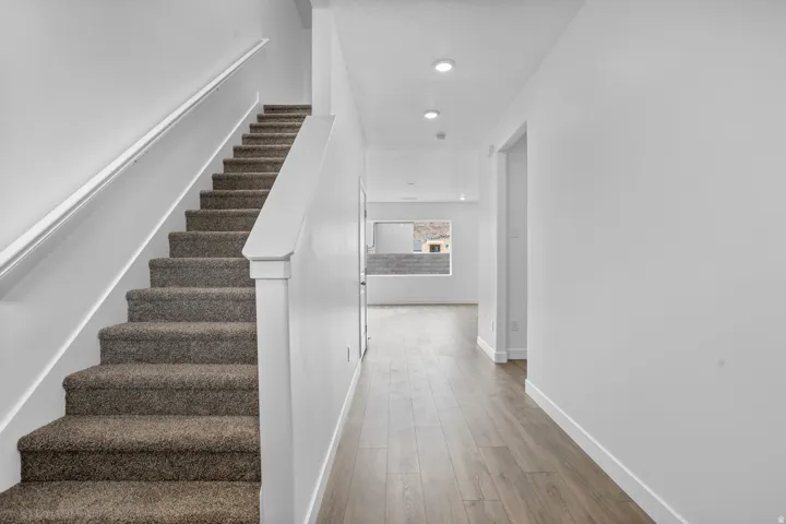 Staircase with carpeted treads and a white handrail
