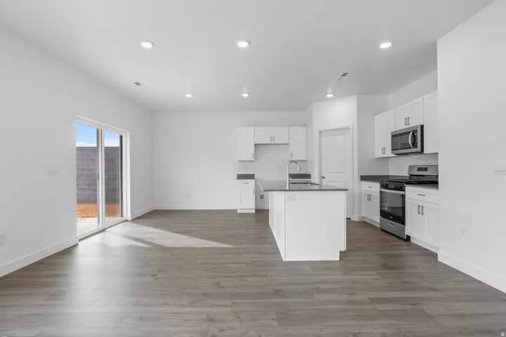 Open-concept living area with wood-finish flooring, recessed lighting, and a sliding glass door
