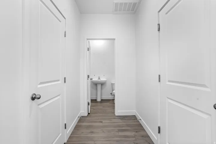 Hallway featuring wood-finish flooring, white paneled doors, and a neutral color palette