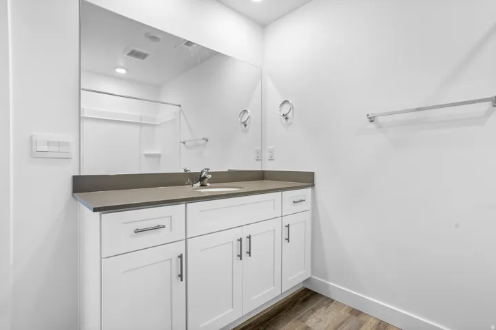 White vanity with under-sink storage, integrated sink, and gray countertop