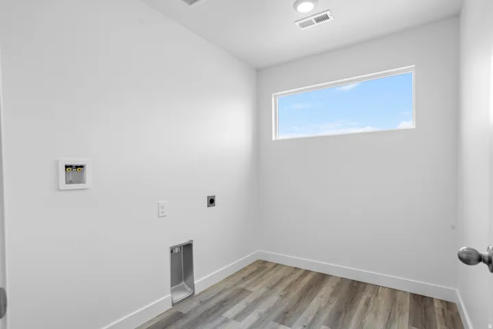 Laundry area with wood-finish flooring, a high horizontal window, and recessed ceiling lighting