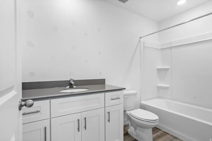 White shaker-style vanity with a gray countertop, integrated sink, and chrome faucet