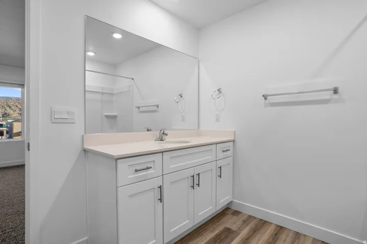 White vanity with shaker-style cabinetry, a single basin sink, and a light-toned countertop