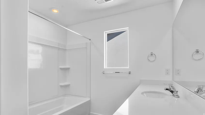 White vanity with a solid surface countertop, an undermount sink, and a chrome faucet