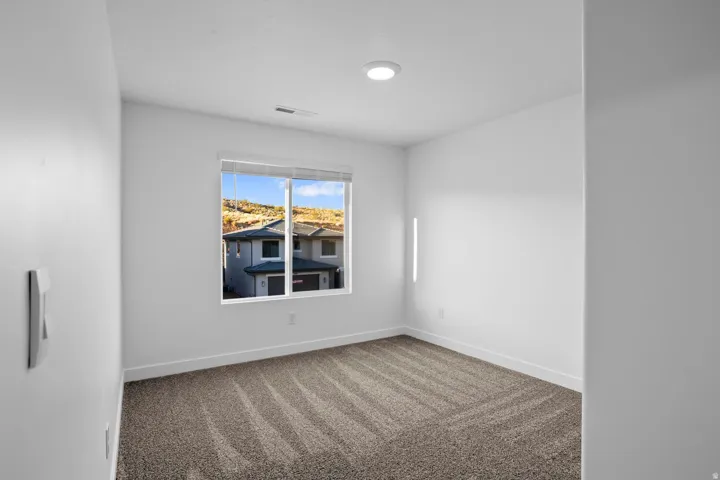 Recessed ceiling lighting, textured carpeting, contemporary window, white walls, and white trim