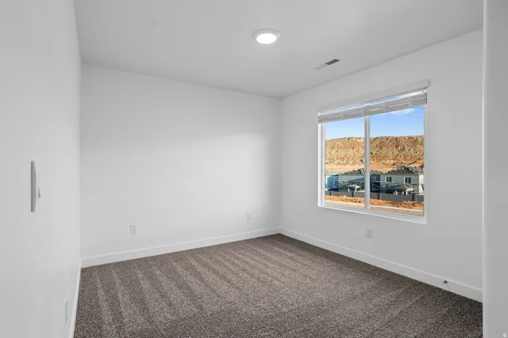 Bright interior with a window featuring a mountain backdrop, neutral carpet, and white walls