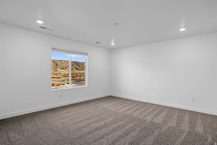 Recessed ceiling lighting, white painted walls, patterned carpet flooring, and a window with mountain scenery