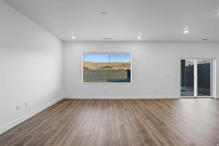 Recessed lighting, wood-finish flooring, sliding glass door, and a window with horizontal blinds