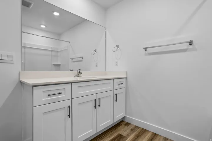 White vanity with shaker-style cabinetry, a light-toned countertop, and an integrated sink with a chrome faucet