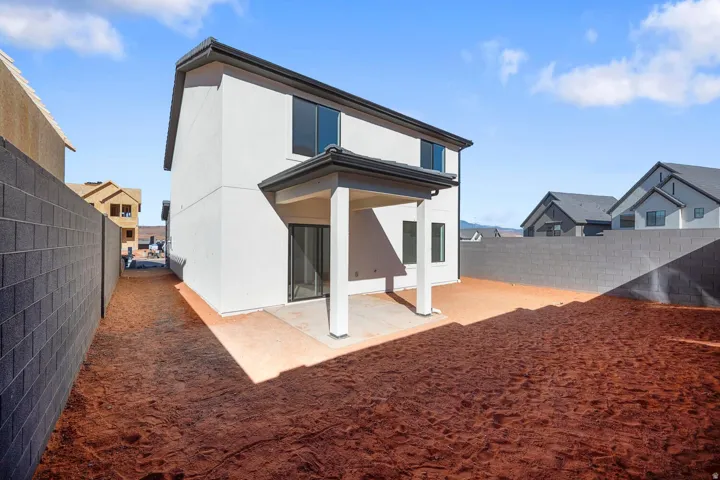 Two-story stucco exterior with a covered patio, multiple windows, and dark-framed soffits