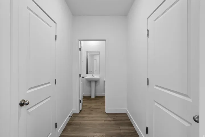 Hallway with wood-finish flooring, white walls, and white two-panel doors