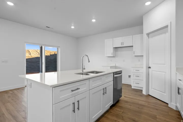 Kitchen featuring white shaker cabinetry, stainless steel dishwasher, wood-finish flooring, recessed lighting, and sliding patio door