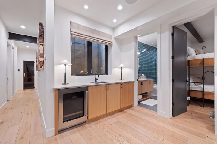 Integrated wet bar with wood-finish cabinetry, built-in beverage refrigerator, and stone countertop