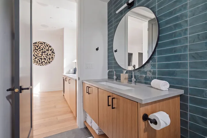 Bathroom featuring a wood-finish vanity with a single basin, a light-toned countertop, and a circular mirror