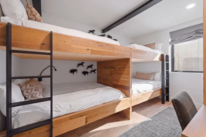 Custom-built bunk beds with wood-finish framing and integrated ladders
