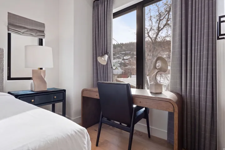 Built-in desk area with wood-finish top and a large window, complemented by grey patterned drapes