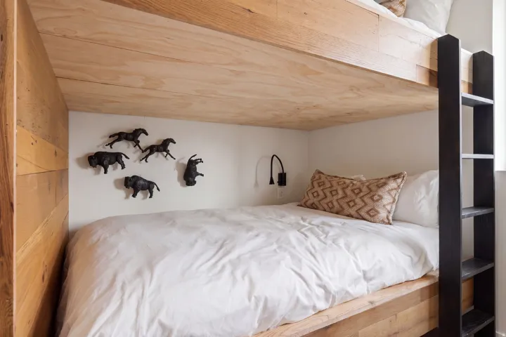 Built-in bunk bed with natural wood-finish frame and an integrated black ladder