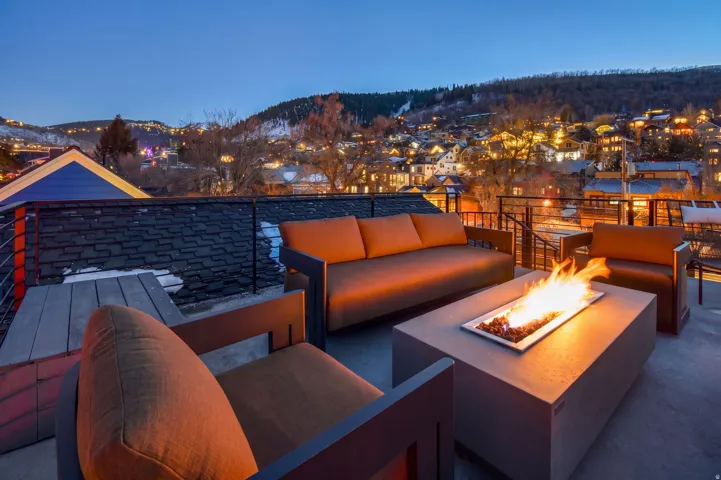Rooftop deck featuring a built-in fire pit, metal railing, and permanent hardscaping