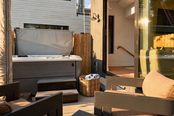 Outdoor patio featuring a hot tub with steps, privacy fencing, and direct access to interior with wood-finish flooring