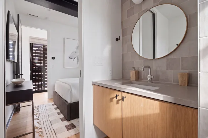 Bathroom vanity featuring a built-in rectangular sink, light wood cabinetry, and a full-height tile backsplash