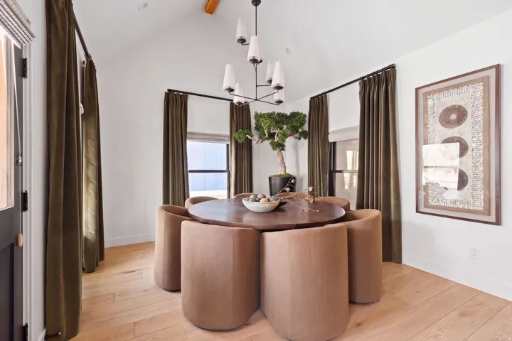 Vaulted ceiling with exposed wood beam, light wood-finish flooring, and a modern chandelier