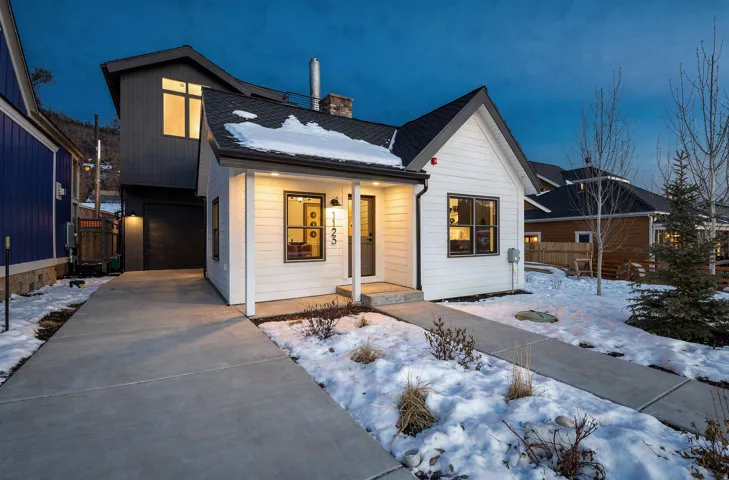 Modern farmhouse-style exterior with white horizontal siding and a dark roof