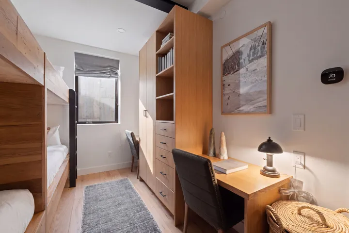 Built-in wood bunk beds, wood-finish flooring, built-in desk, built-in storage cabinetry, and window with privacy shade