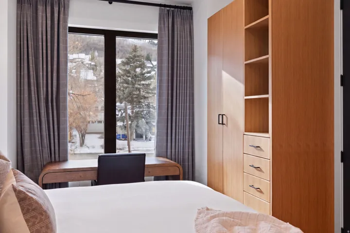 Expansive window with black trim, built-in desk, and wood-finish cabinetry featuring open shelving and pull-out drawers