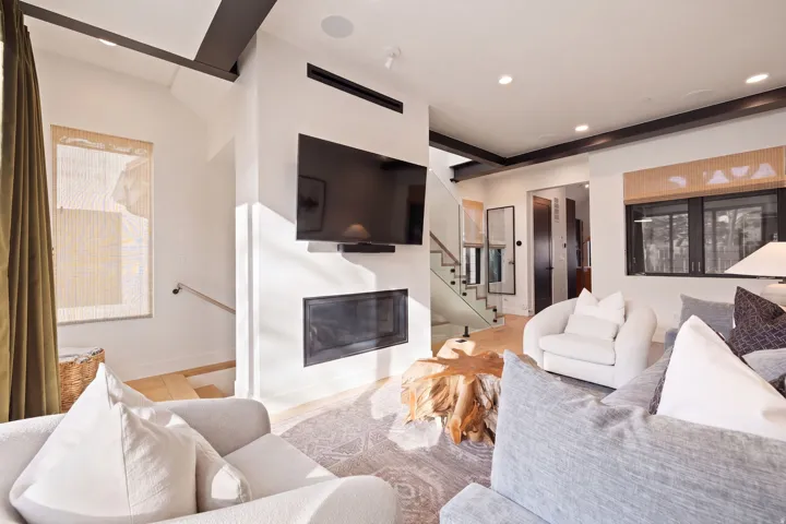 Integrated fireplace, recessed lighting, wood-finish flooring, glass panel staircase, exposed ceiling beams