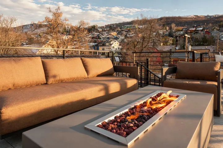 Rooftop patio featuring a linear fire pit, metal railings, and a hard surface deck