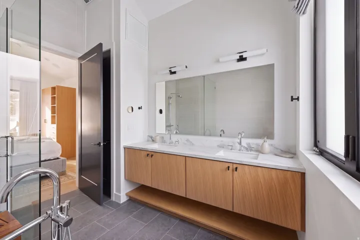 Floating dual-sink vanity with wood-finish cabinetry, stone countertop, and contemporary lighting