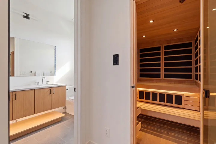 Wood-paneled sauna with built-in bench seating and recessed lighting