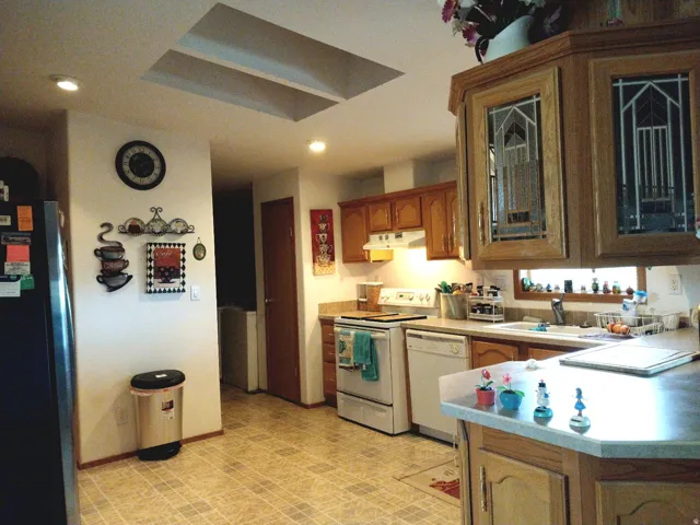 Kitchen featuring wood cabinetry, overhead lighting, skylights, tile flooring, and a double-basin sink