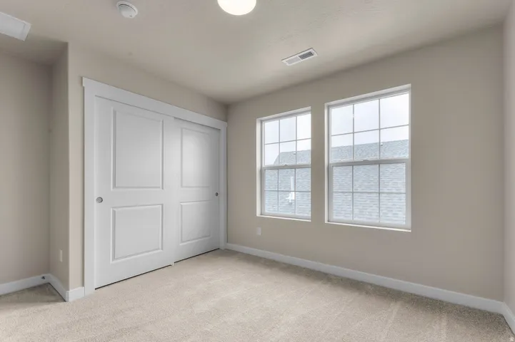 Soft neutral-toned walls, white trim, two white-framed windows, and light-colored carpet