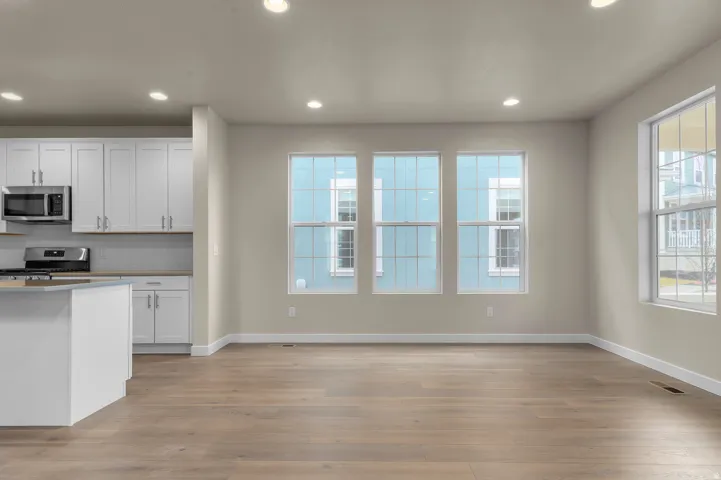 Open-concept living area with wood-finish flooring, recessed lighting, and multiple windows