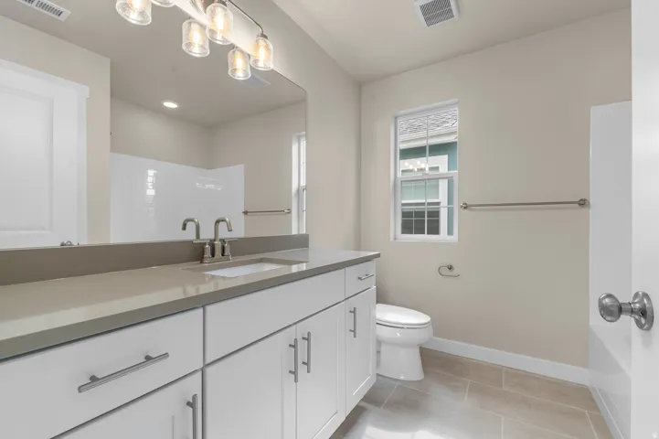 White vanity with brushed nickel hardware, light-toned countertop, and undermount sink