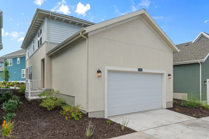 Two-story stucco and siding exterior with a pitched roof, attached garage, and exterior lighting fixtures