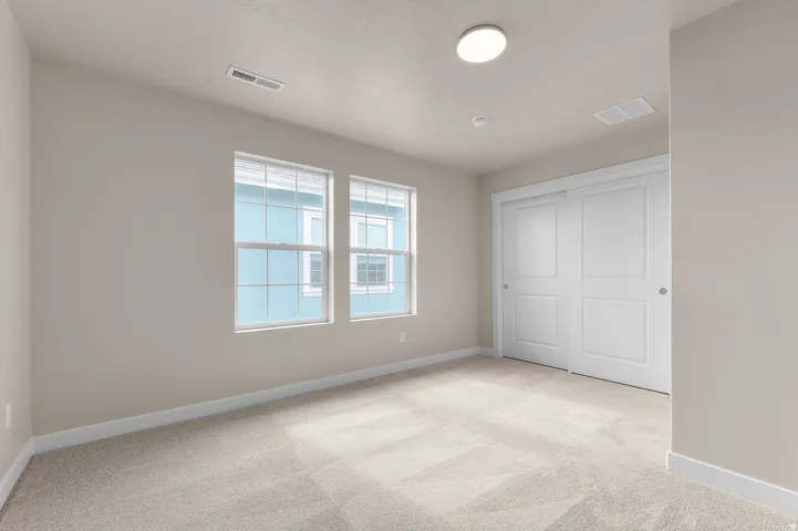 Neutral wall paint, light-toned carpet, dual pane windows with grid pattern, and white sliding closet doors