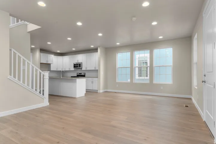 Open-concept living space featuring wood-finish flooring, recessed lighting, and multiple windows
