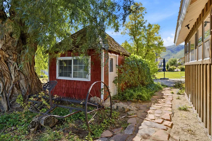Red shingle-sided shed with a wood shingle roof and white-framed windows