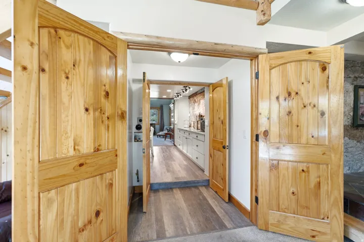 Natural wood double doors with arched top panels, wood-finish flooring, and recessed lighting