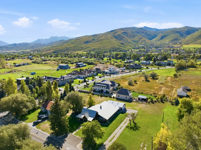 Expansive property with mountainous terrain, lush green fields, and a clear blue sky