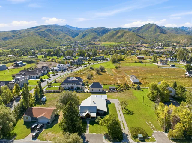 Expansive property with a green lawn, mature trees, and mountainous scenery