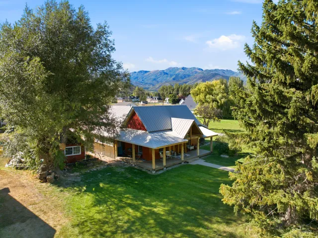 Barn-style residence featuring a metal roof, extended covered porch, and red siding