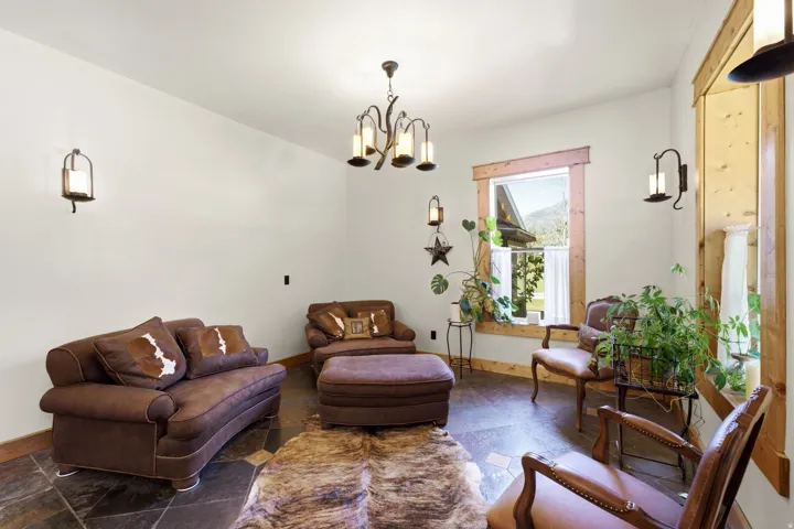 Slate tile flooring, natural wood window trim, exposed wood window framing, ceiling-mounted chandelier, and wall-mounted sconces