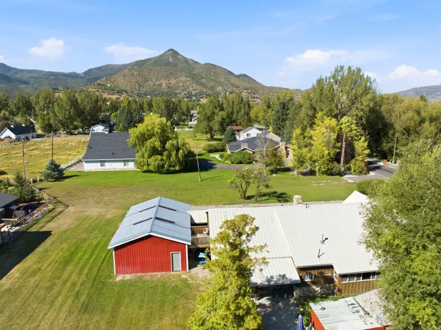 Expansive property with a red barn garage, a main residence featuring a metal roof, and a mature treed landscape