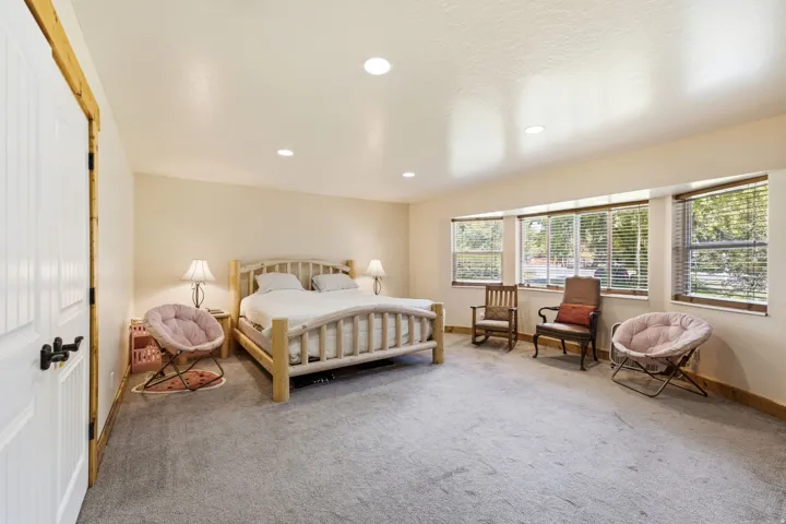 Recessed lighting, multiple windows with blinds, light-toned walls, wood-finish trim, and gray carpet