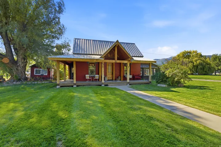 Red exterior featuring a covered porch with natural wood pillars, a metal roof, and a separate outbuilding